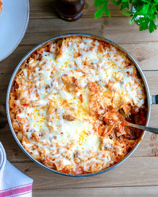 Skilled Baked pasta with melted mozzarella cheese on top and a spoon ready to take the next serving